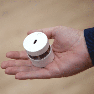 De grootte van een compacte rookmelder tenopzichte van een hand. De rookmelder is kleiner dan de volwassen hand van een man.